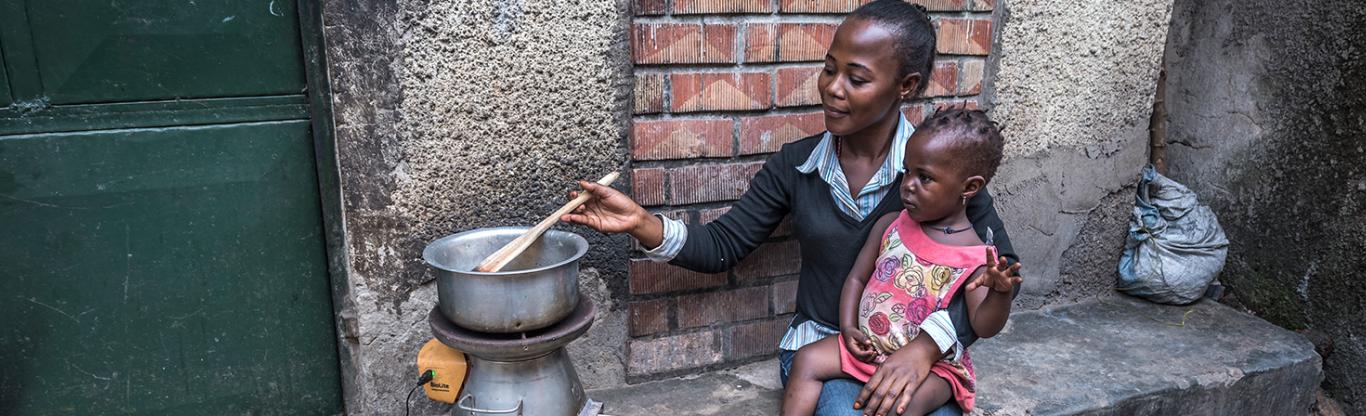 woman and child sitting outside their home cooking
